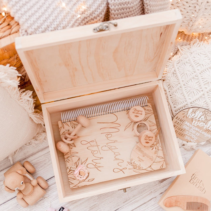 Large wooden box for keepsakes. Open view. Inside is a etched wooden baby book for name Morgan, a wooden rattle and trinket boxes. 
