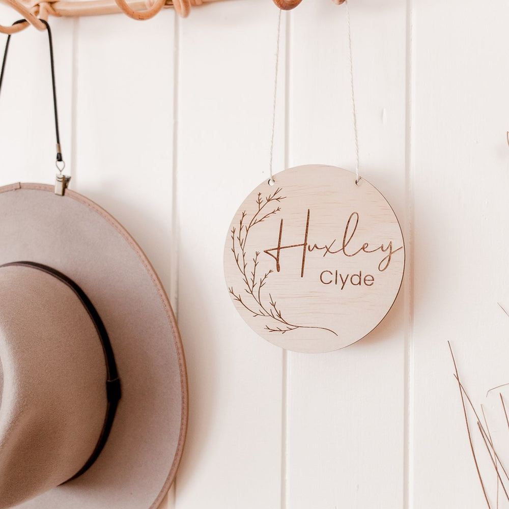 Hello Fern whimsical custom wooden name plaque shown with holes and twine, hanging on baby's bedroom or nursery wall.