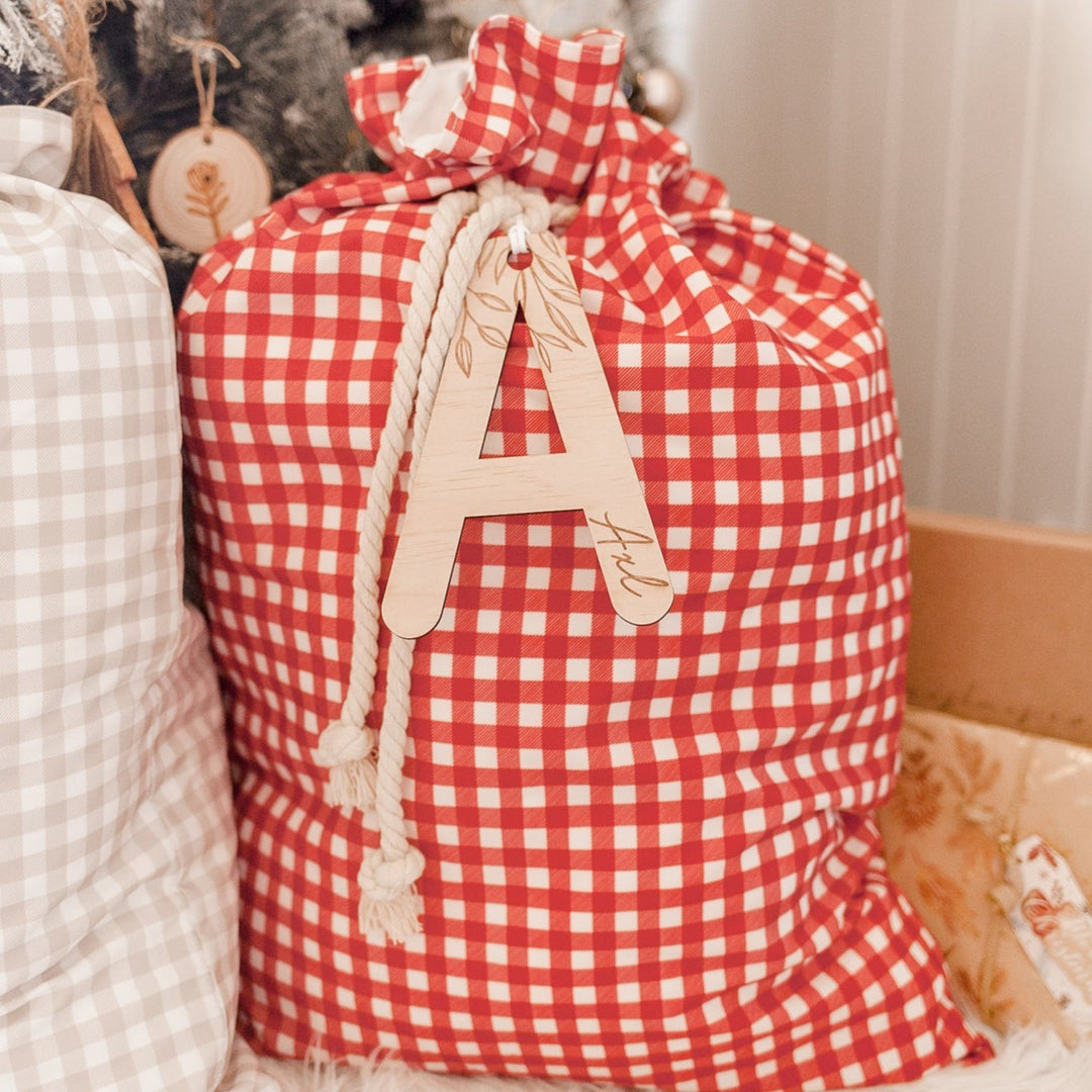 Red Christmas Santa sac with wooden letter 'A' plaque and name 'Axl' etched into plaque.
