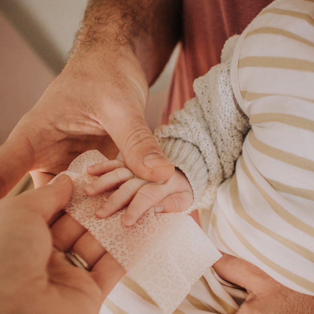 Dad wiping baby's hands with non-toxic wipe from inkless print kit.