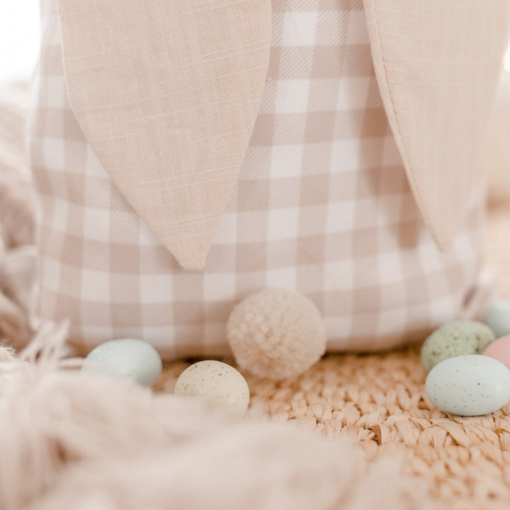 Close up of beige gingham Easter sack with pom pom tail and Easter eggs.