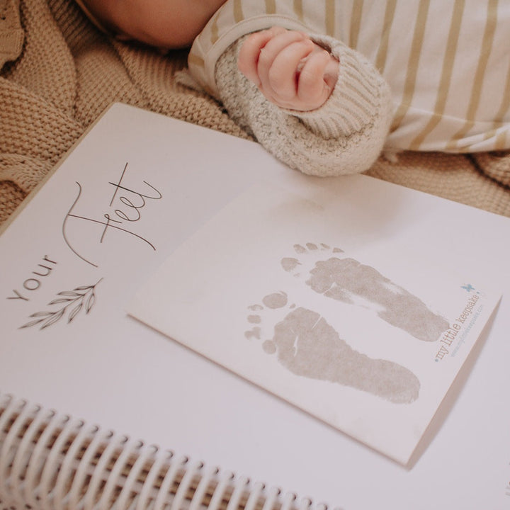Hello Fern and My Little Keepsake inkless print kit showing baby's footprints inside Hello Fern Your Story baby book.
