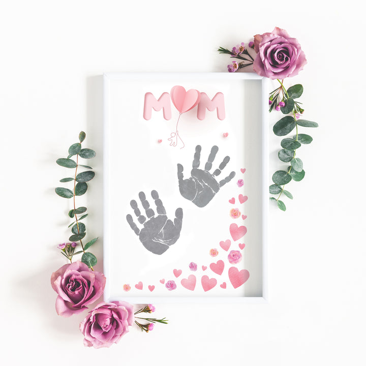 Flatlay showing "MUM" handprint sheet in fram with flowers surrounding from inkless print kit Mother's Day edition.