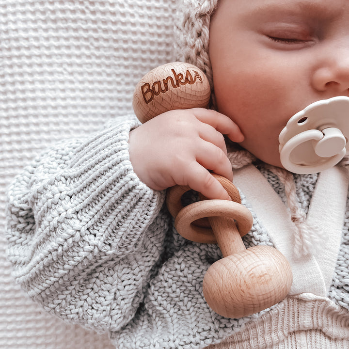 Baby Banks holding custom wooden baby rattle.