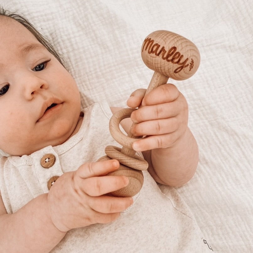 Baby Marley holding custom wooden baby rattle.